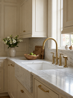 Modern kitchen with marble countertop, gold faucet, and decorative elements.