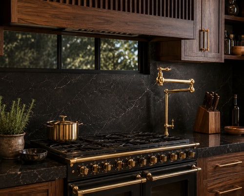 A luxury kitchen scene featuring a black gas range with polished brass controls and a matching brass high-arc faucet, set against a dark marble backsplash and dark wood cabinetry.