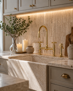 Modern kitchen with gold faucet, marble countertop, and decorative elements.