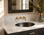 Bathroom vanity with marble countertop, black sink, gold faucet, and decorative mirror.