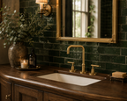 Bathroom vanity with gold fixtures, green tiled wall, and decorative elements.
