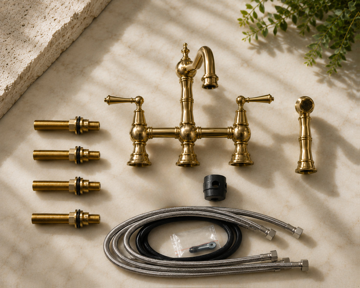 Set of gold plumbing fixtures on a light stone surface with shadows and greenery.
