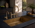 Gold kitchen sink and faucet set against a dark countertop with decorative elements.