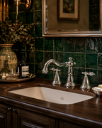 Bathroom sink with silver faucet against a green tiled wall.