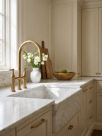 Modern kitchen with marble countertop, gold faucet, and decorative elements.