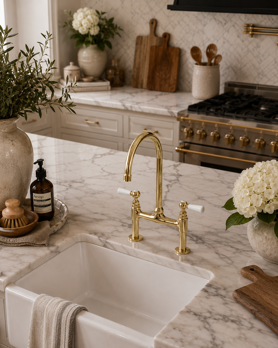 Kitchen with marble countertop, gold faucet, and white flowers.