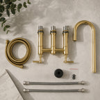 Gold kitchen faucet set with hoses and connectors on a neutral background